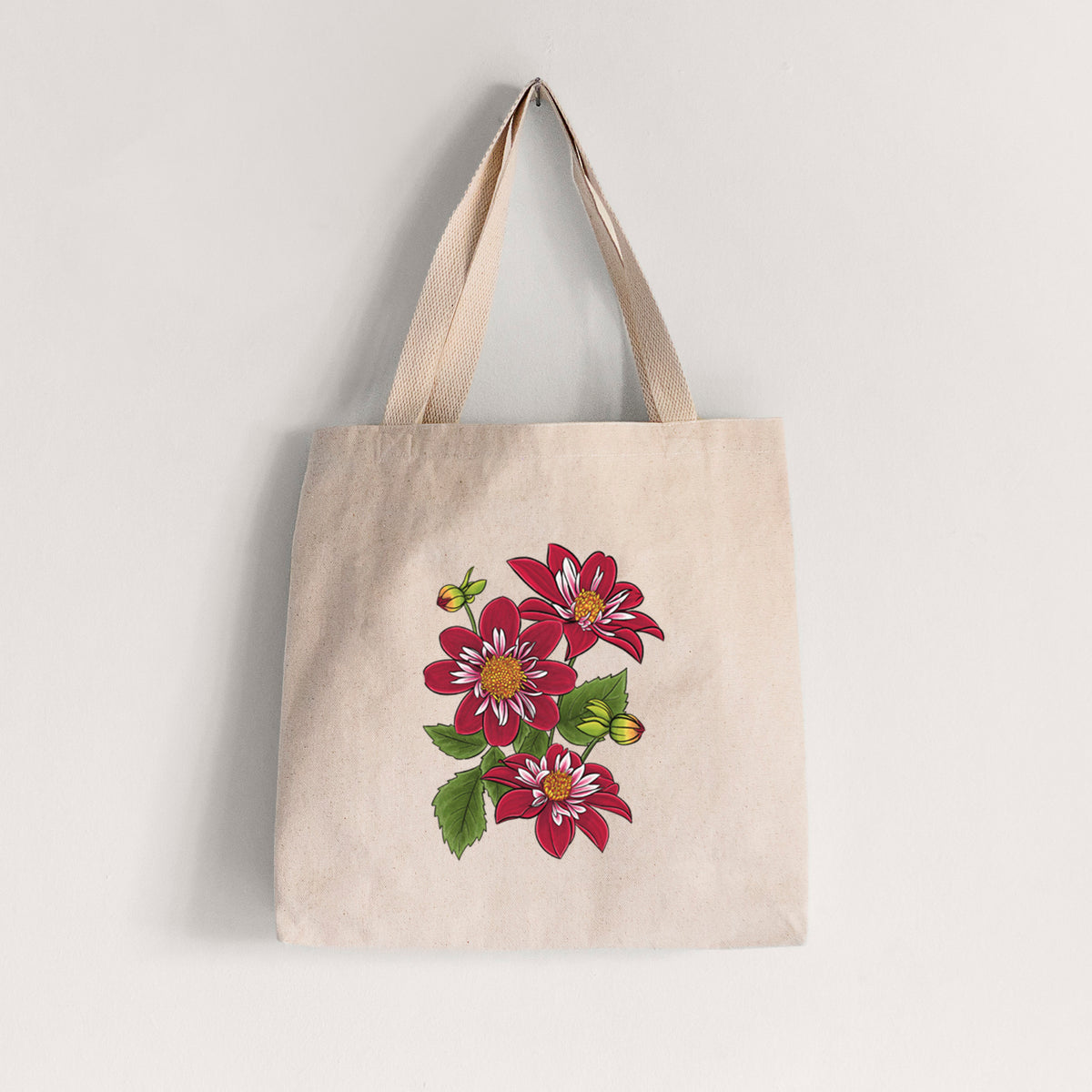 Natural canvas tote bag printed with a full-color illustration of deep red dahlia flowers with green leaves and a small bee.