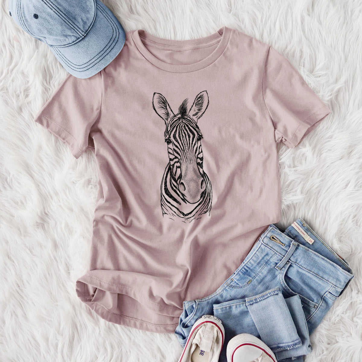 Women's relaxed fit cotton t-shirt printed with a detailed black ink portrait of a Damara zebra facing forward, styled flat on a white faux fur rug with jeans.