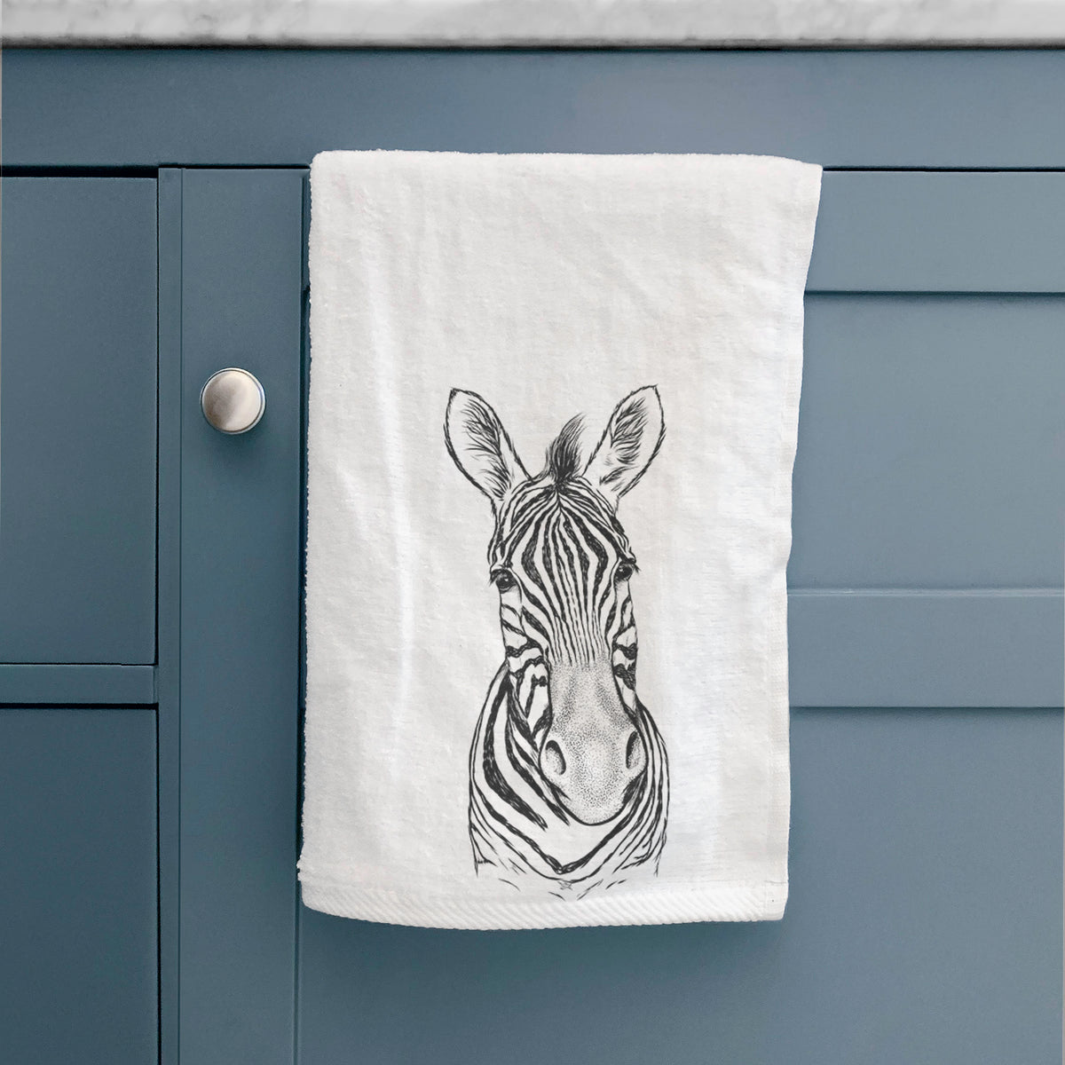 White hand towel printed with a detailed black ink portrait of a Damara zebra facing forward, hanging on a cabinet door.