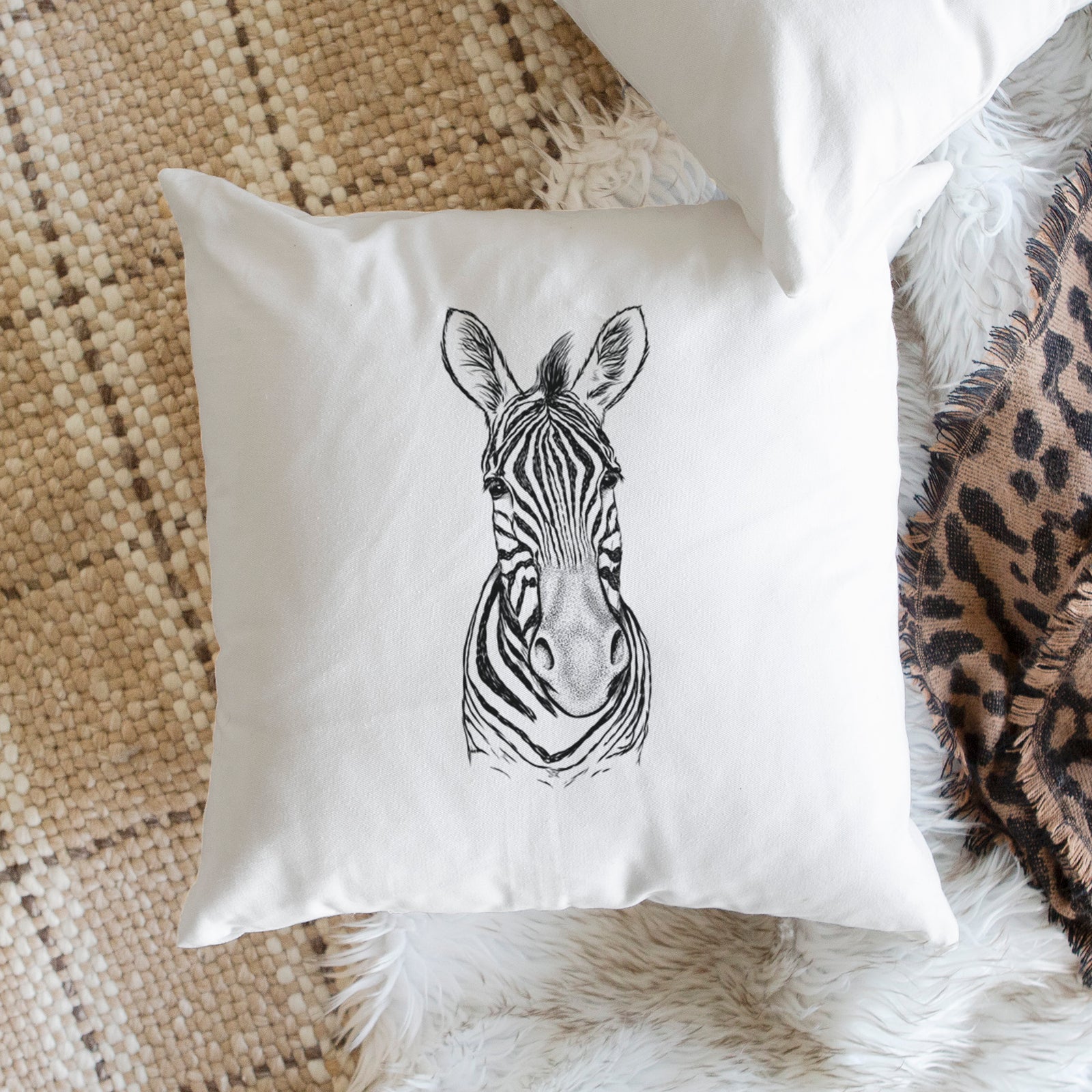 White pillow cover printed with a detailed black ink portrait of a Damara zebra facing forward, on a bench beside plants.