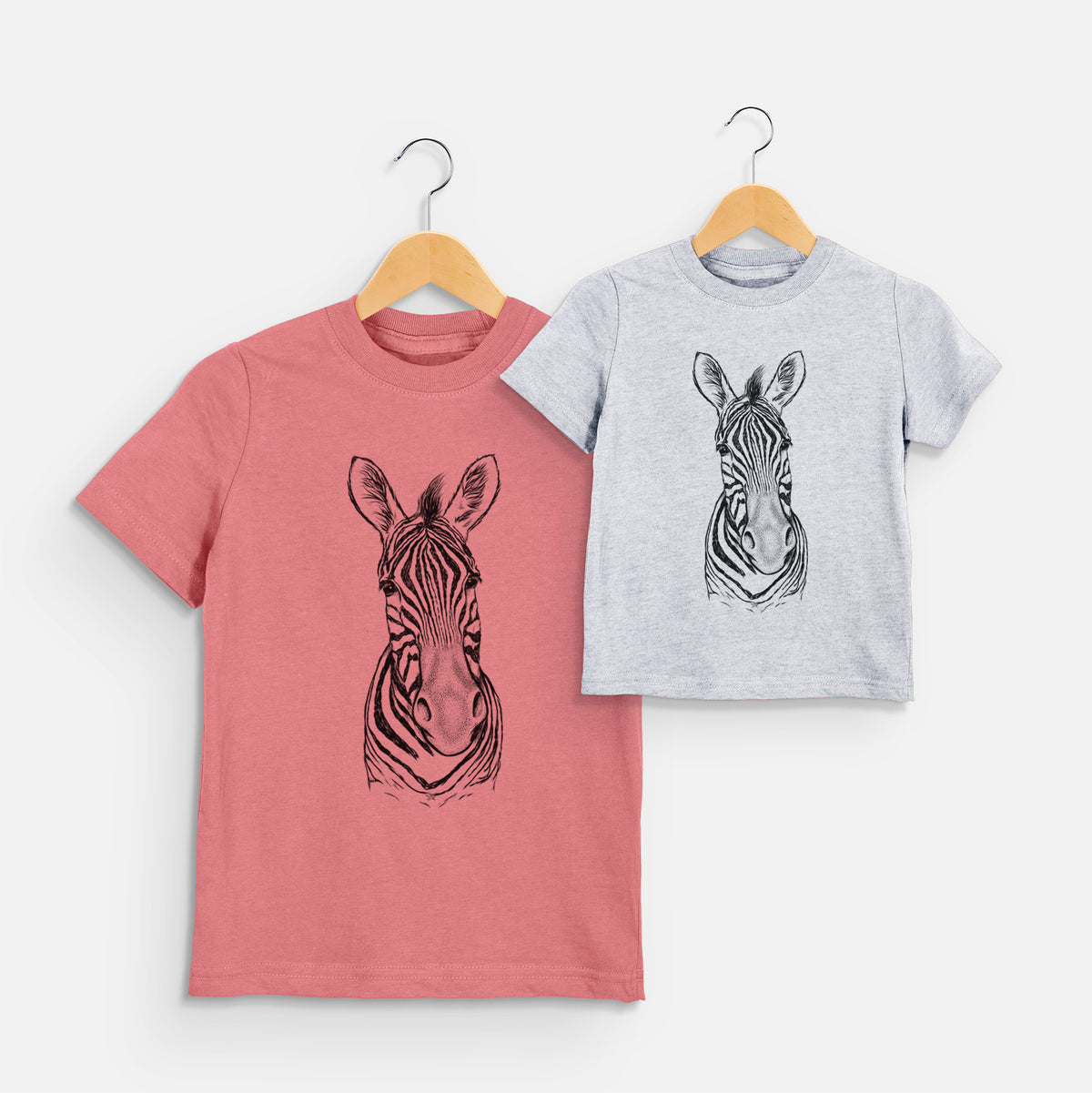 Two youth t-shirts in different colors on hangers, printed with a detailed black ink portrait of a Damara zebra facing forward.