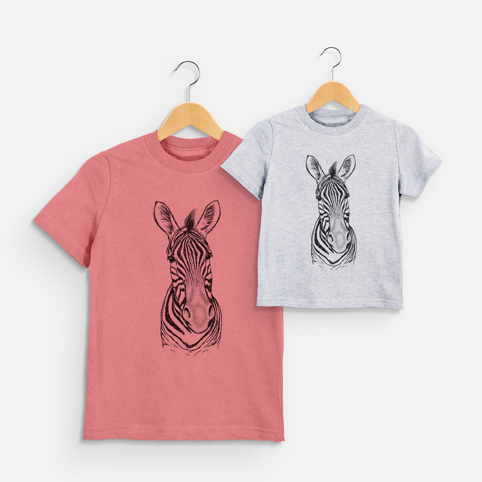 Two youth t-shirts in different colors on hangers, printed with a detailed black ink portrait of a Damara zebra facing forward.