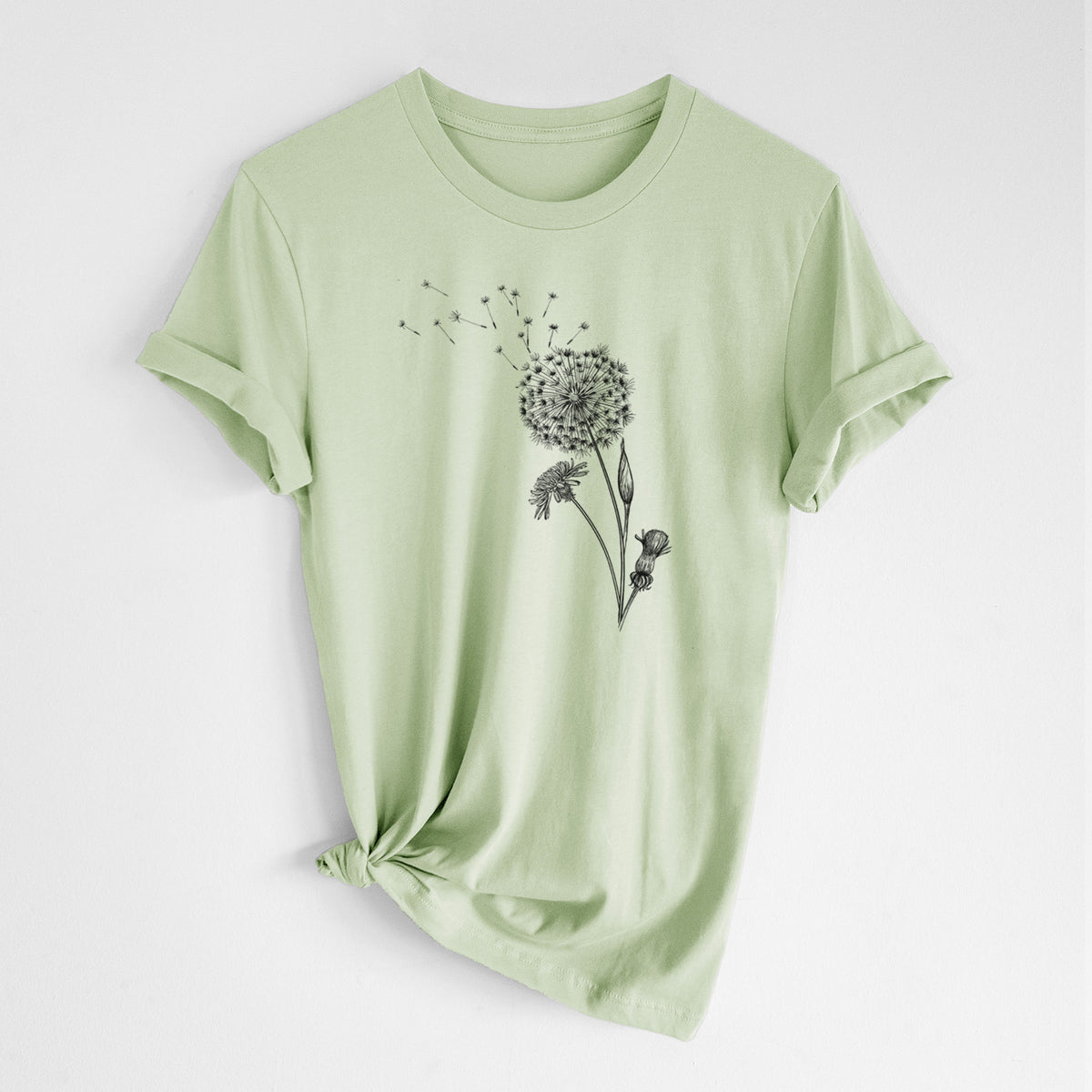 Spring green lightweight cotton t-shirt laid flat with the sleeves rolled, printed with a black ink line drawing of a dandelion seed head with seeds blowing away.