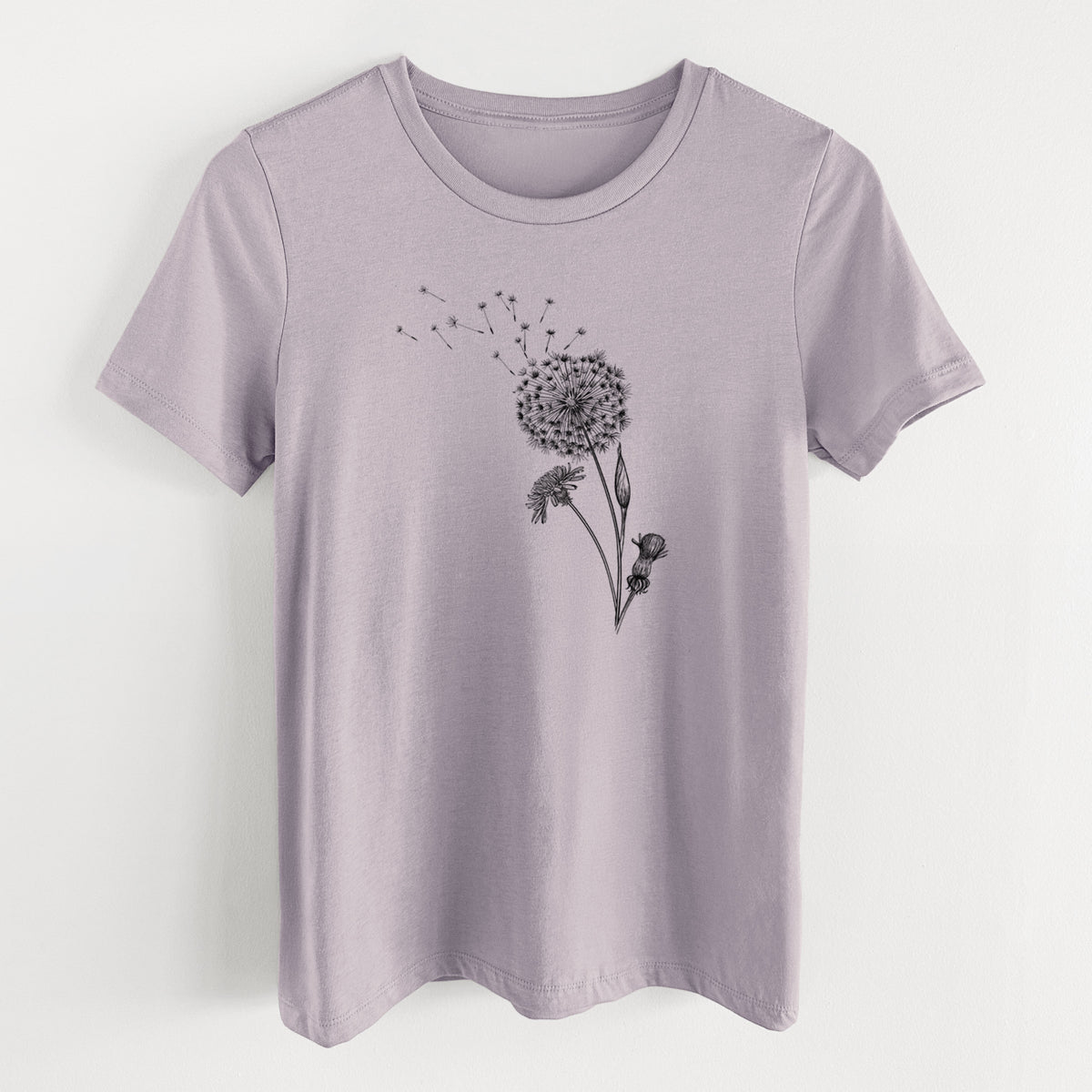 Light violet women's relaxed fit cotton t-shirt laid flat, printed with a black ink line drawing of a dandelion seed head with seeds blowing away.