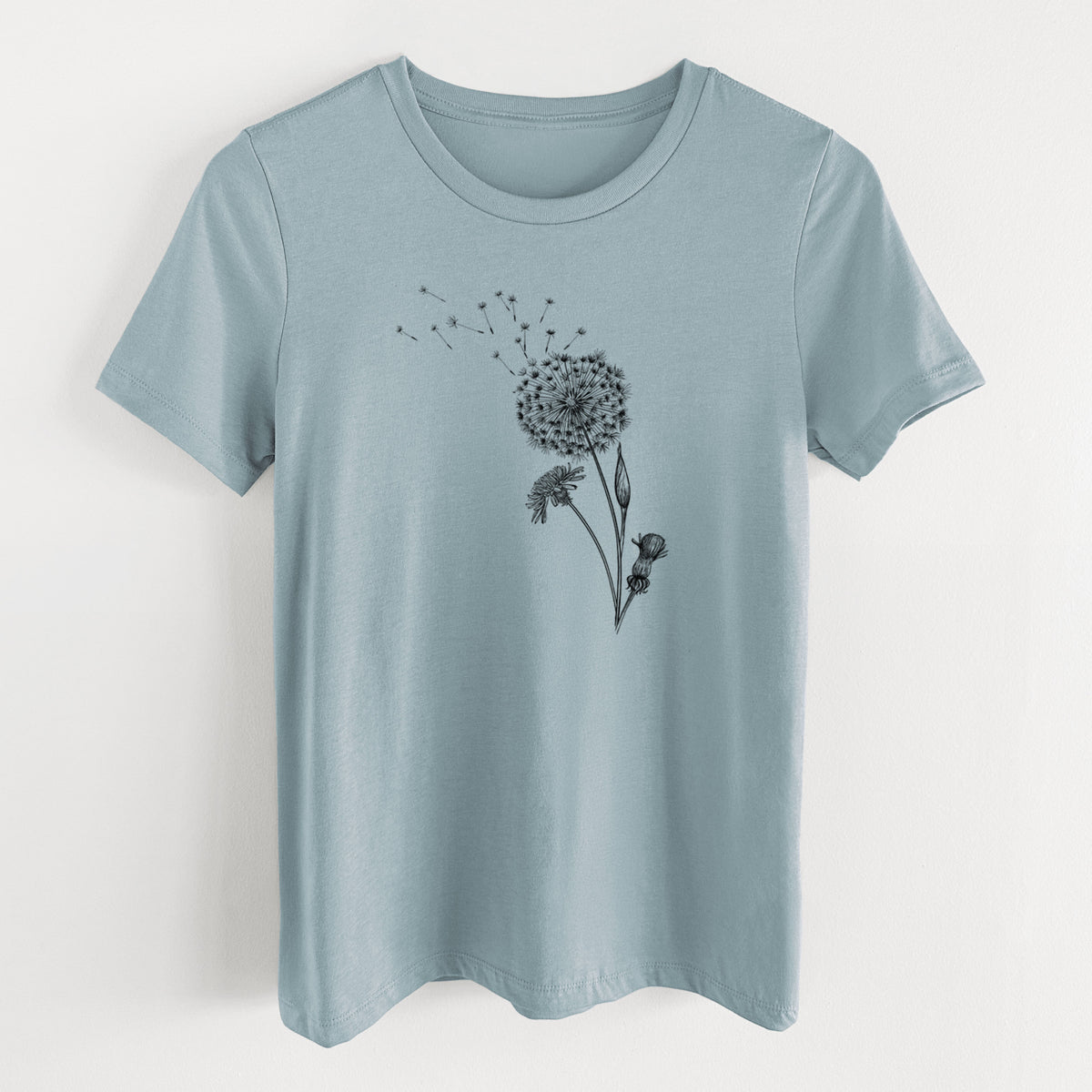 Vintage denim women's relaxed fit cotton t-shirt laid flat, printed with a black ink line drawing of a dandelion seed head with seeds blowing away.