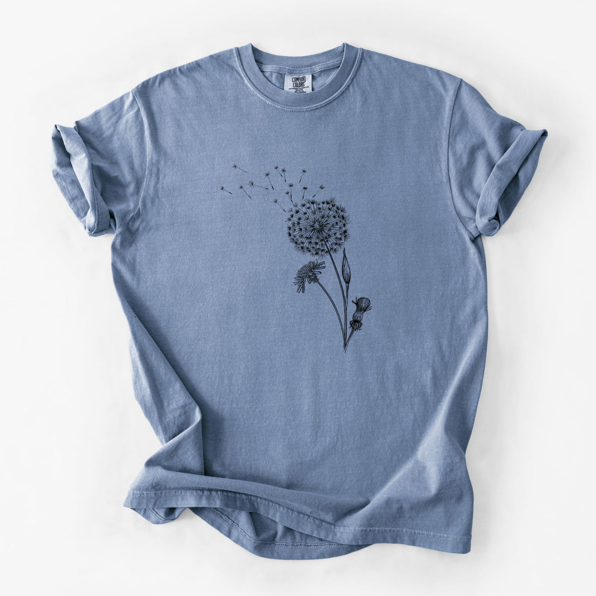 Blue jean Comfort Colors t-shirt laid flat, printed with a black ink line drawing of a dandelion seed head with seeds blowing away.