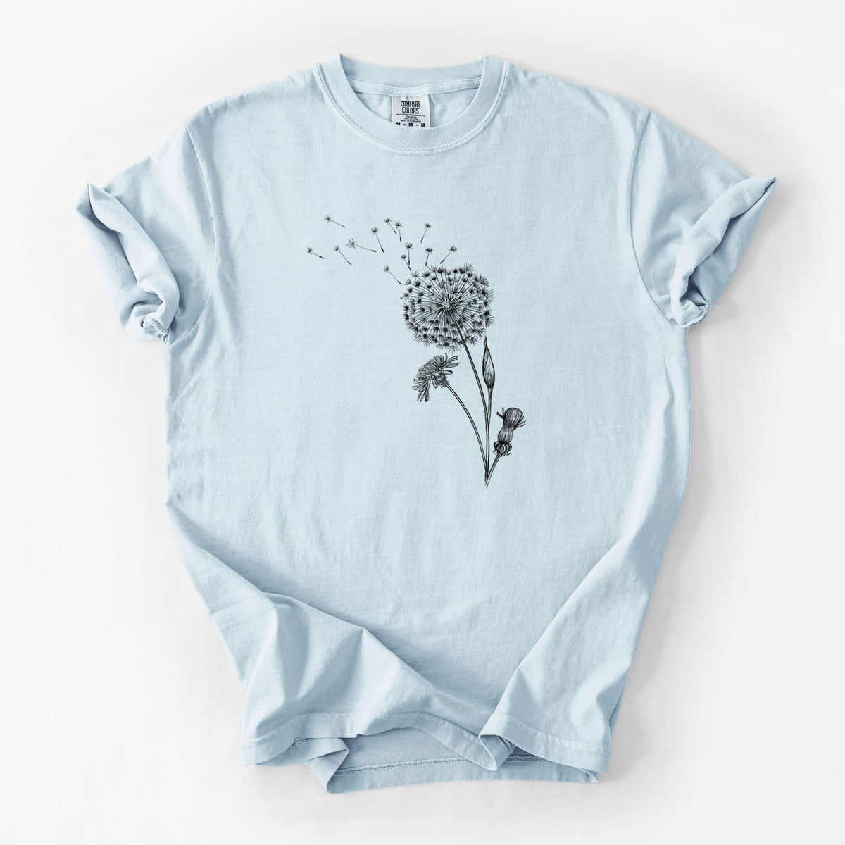 Chambray blue Comfort Colors t-shirt laid flat, printed with a black ink line drawing of a dandelion seed head with seeds blowing away.