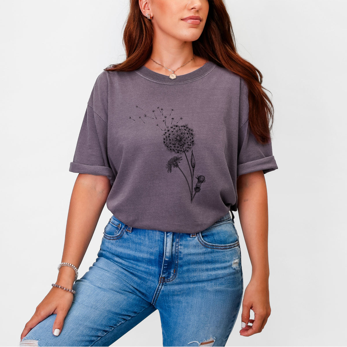 Woman wearing a Comfort Colors t-shirt printed with a black ink line drawing of a dandelion seed head with seeds blowing away.