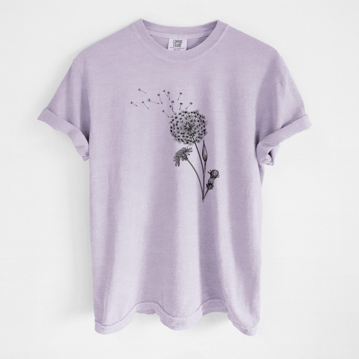 Orchid purple Comfort Colors t-shirt laid flat, printed with a black ink line drawing of a dandelion seed head with seeds blowing away.