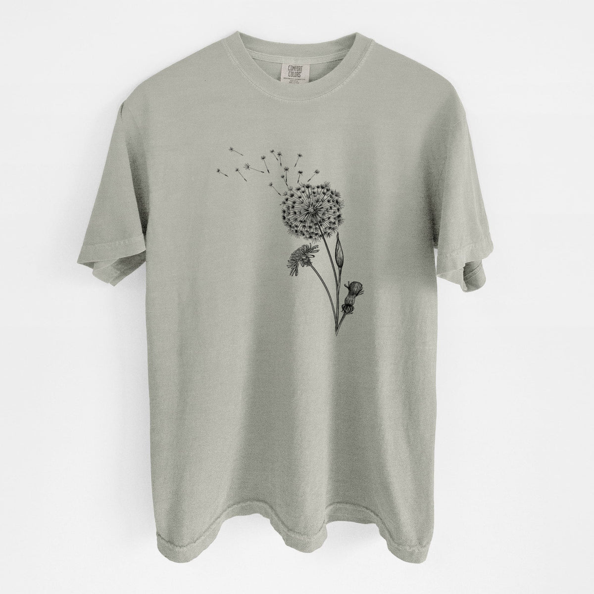 Sandstone beige Comfort Colors t-shirt laid flat, printed with a black ink line drawing of a dandelion seed head with seeds blowing away.