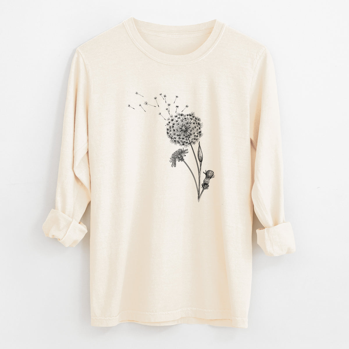 Ivory Comfort Colors long sleeve shirt laid flat with the cuffs rolled, printed with a black ink line drawing of a dandelion seed head with seeds blowing away.