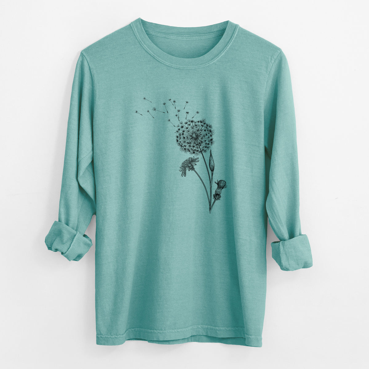 Reef green Comfort Colors long sleeve shirt laid flat with the cuffs rolled, printed with a black ink line drawing of a dandelion seed head with seeds blowing away.