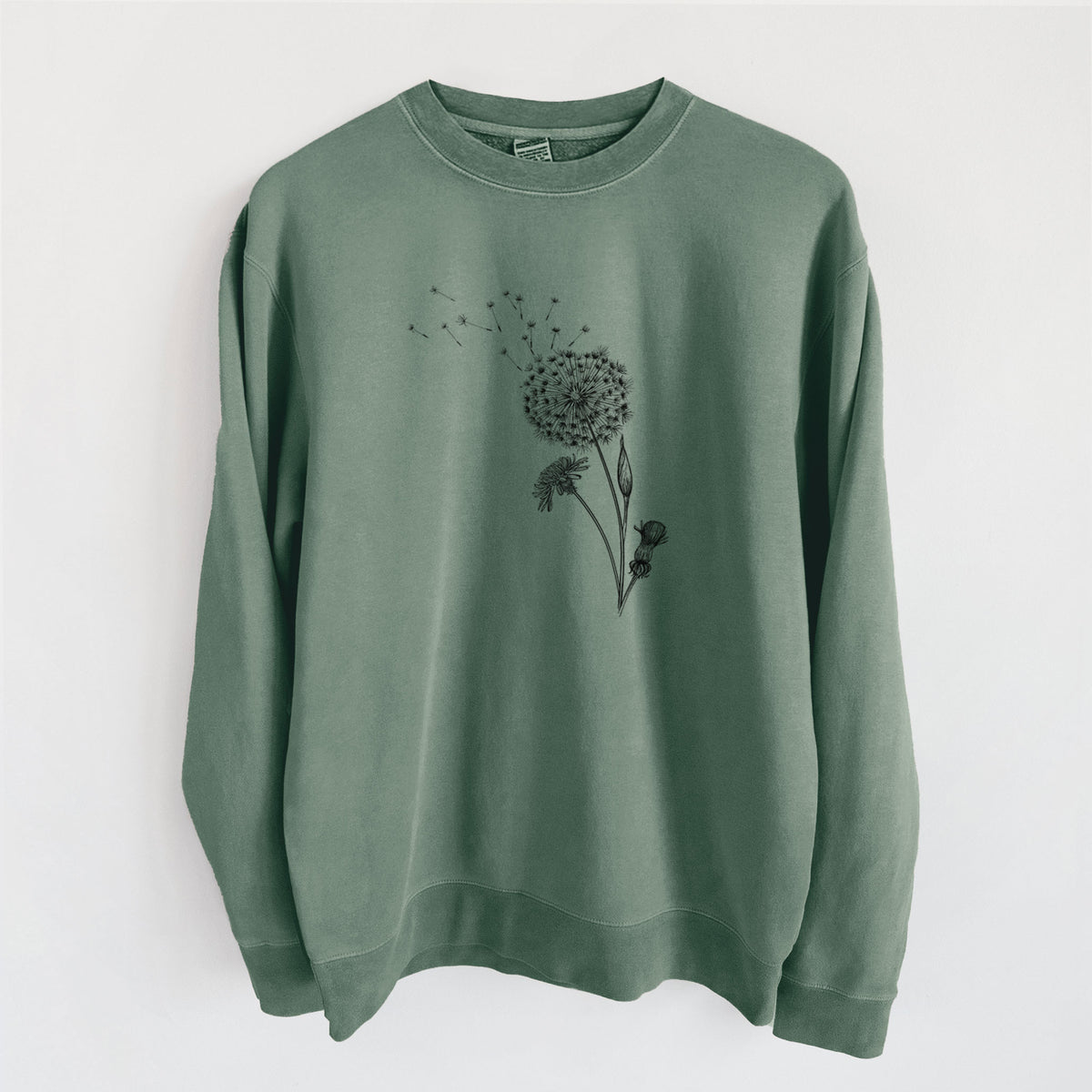 Alpine green pigment dyed crewneck sweatshirt laid flat, printed with a black ink line drawing of a dandelion seed head with seeds blowing away.
