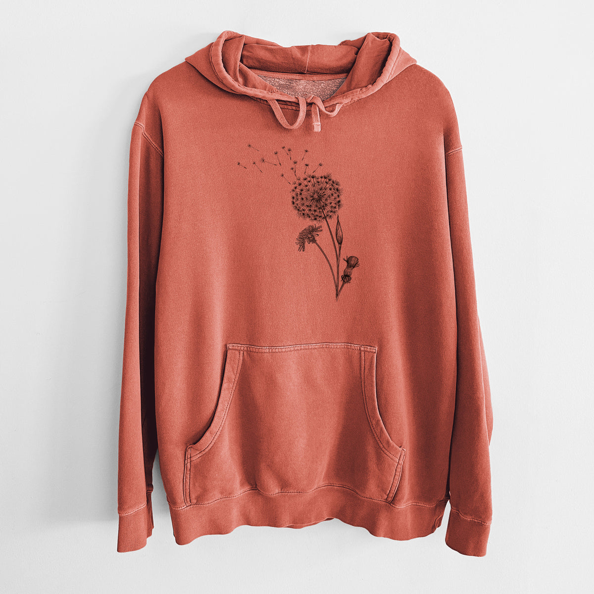 Amber orange pigment dyed hoodie laid flat, printed with a black ink line drawing of a dandelion seed head with seeds blowing away.