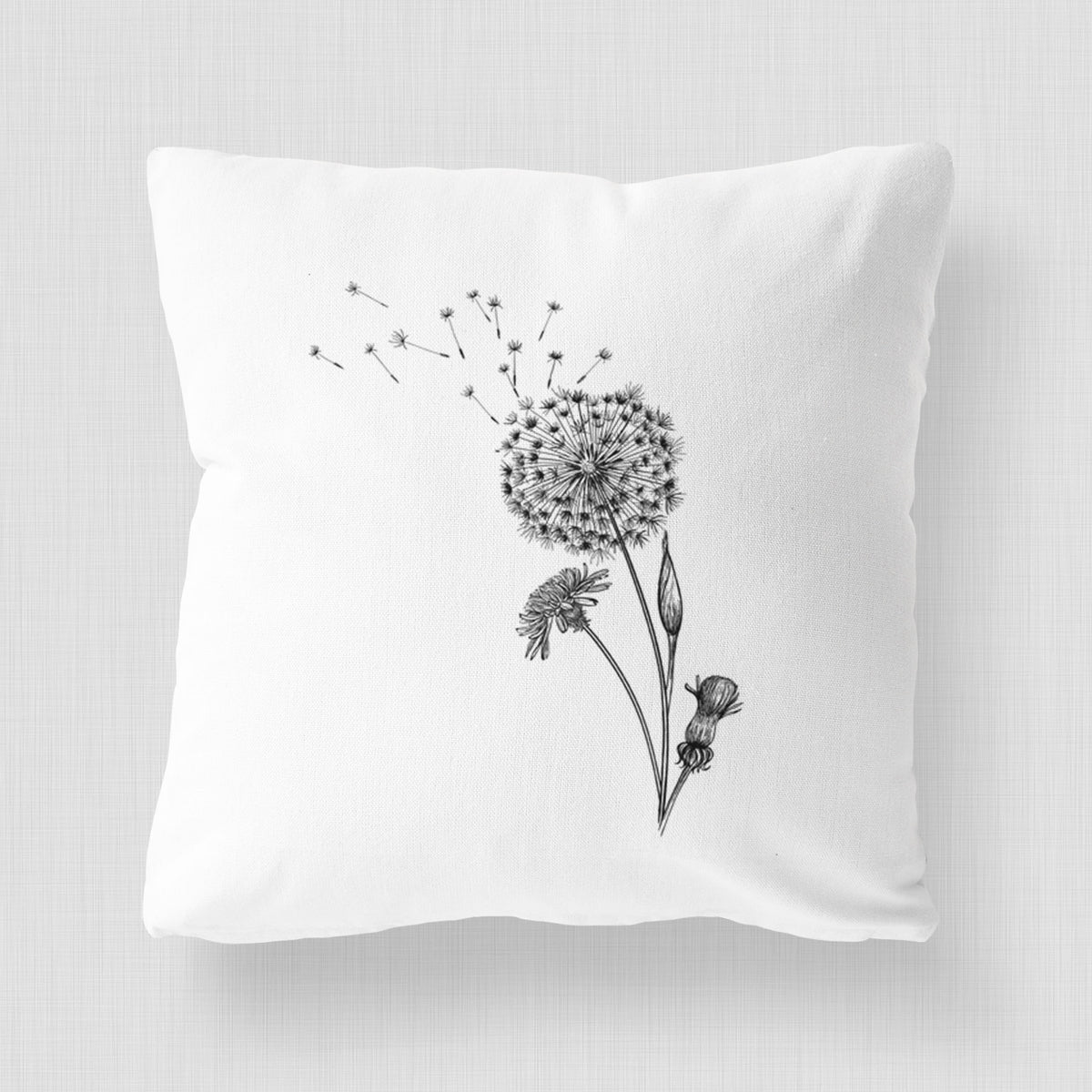White pillow cover printed with a black ink line drawing of a dandelion seed head with seeds blowing away.