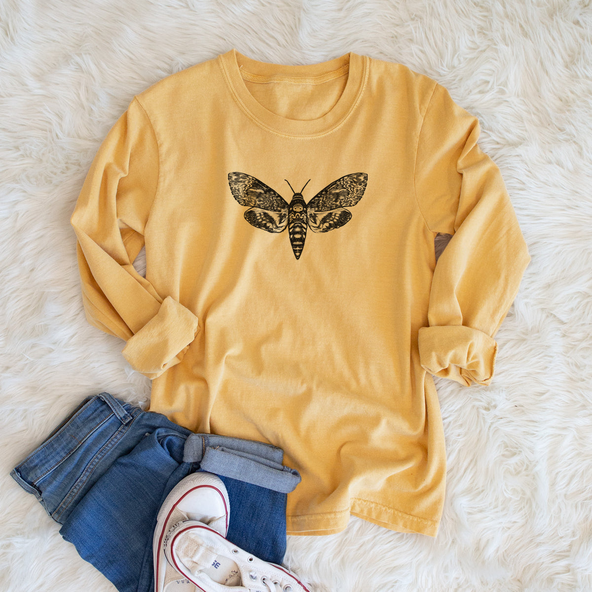 Golden wheat yellow Comfort Colors long sleeve shirt printed with a detailed black ink illustration of a death's-head hawkmoth with its wings spread, shown in a lifestyle photo.