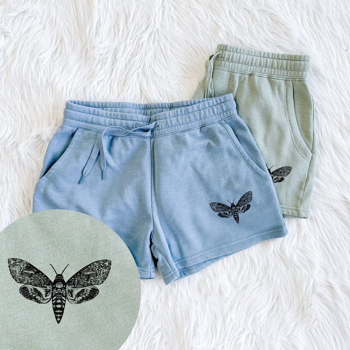 Two pairs of Cali Wave shorts in different colors printed with a detailed black ink illustration of a death's-head hawkmoth with its wings spread, with a close-up of the print.