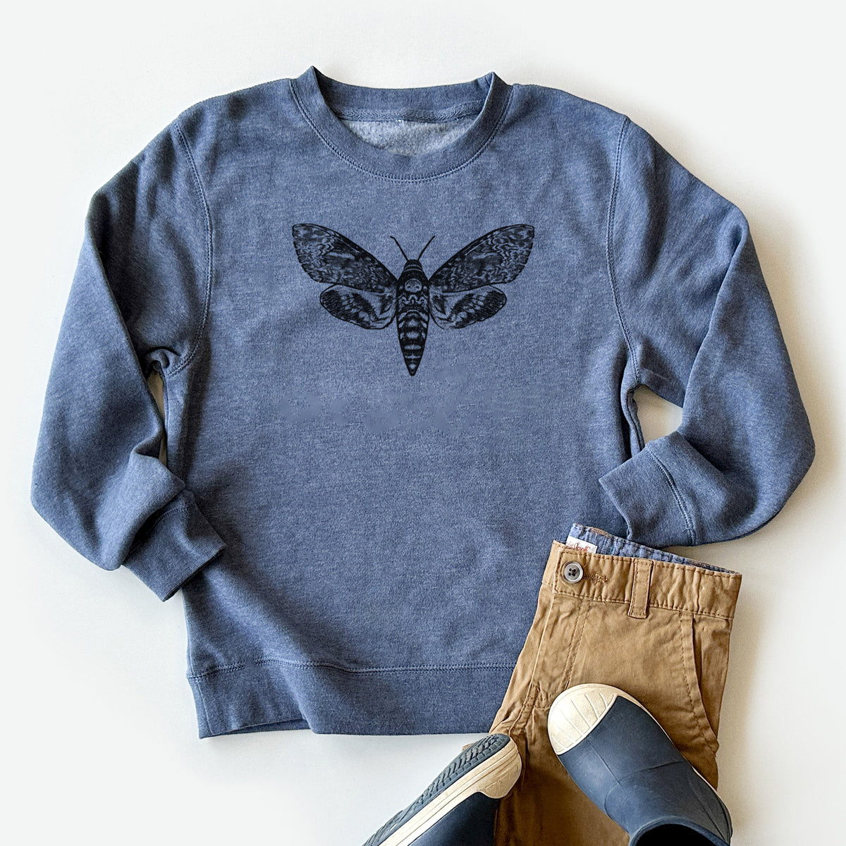 Youth crewneck sweatshirt printed with a detailed black ink illustration of a death's-head hawkmoth with its wings spread, styled flat with khaki pants and shoes.