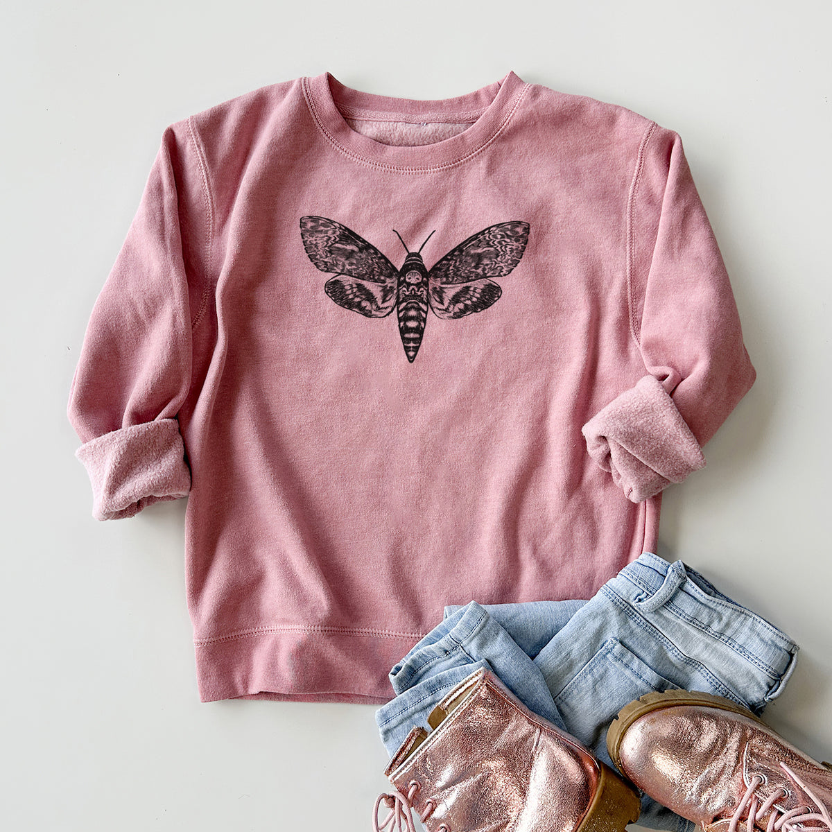 Youth crewneck sweatshirt printed with a detailed black ink illustration of a death's-head hawkmoth with its wings spread, styled flat with jeans and boots.