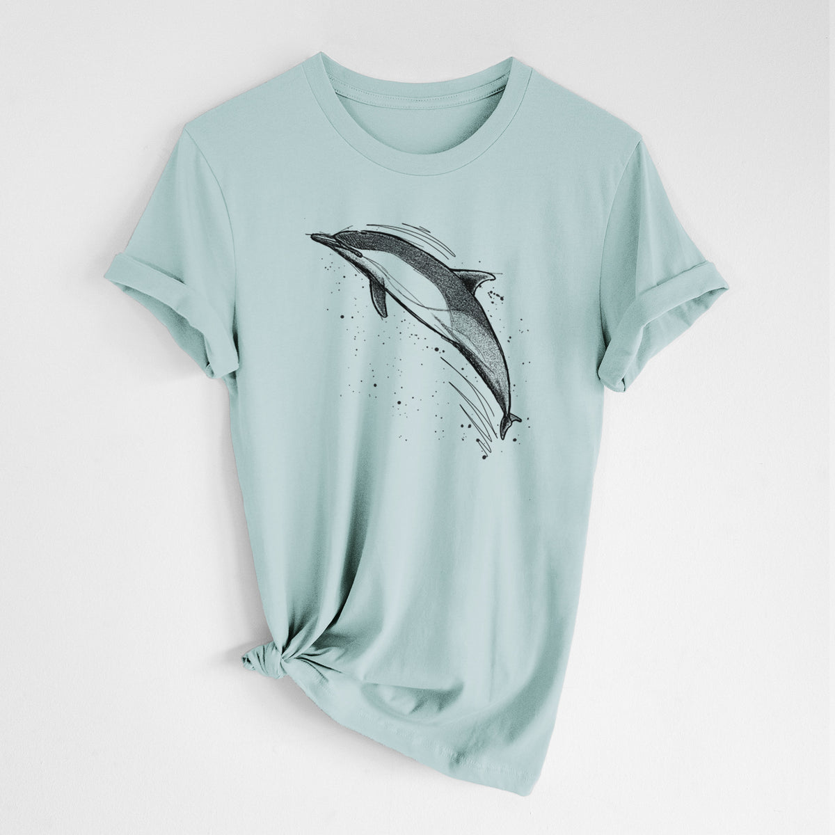 Dusty blue lightweight cotton t-shirt laid flat with the sleeves rolled, printed with a black ink illustration of a common dolphin leaping, with ink splatters.