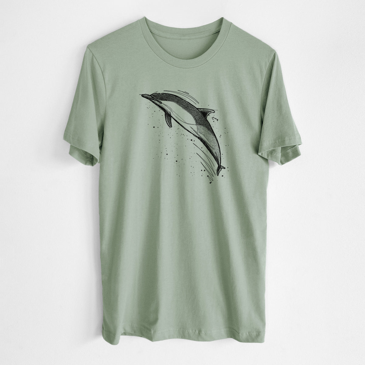 Sage green lightweight cotton t-shirt laid flat, printed with a black ink illustration of a common dolphin leaping, with ink splatters.