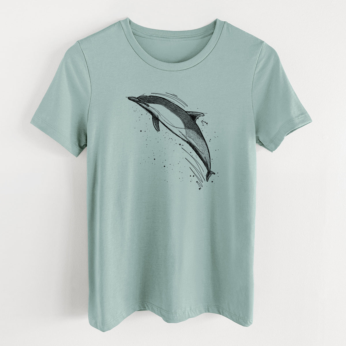 Dusty blue women's relaxed fit cotton t-shirt laid flat, printed with a black ink illustration of a common dolphin leaping, with ink splatters.