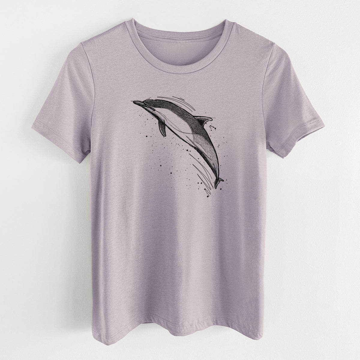 Light violet women's relaxed fit cotton t-shirt laid flat, printed with a black ink illustration of a common dolphin leaping, with ink splatters.