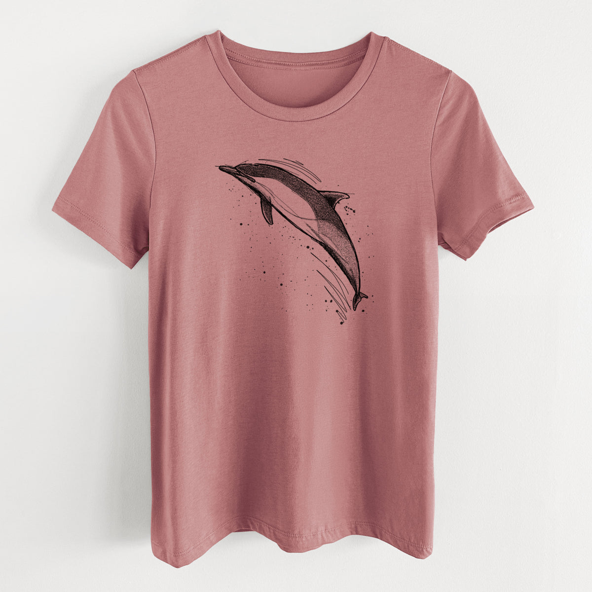 Mauve pink women's relaxed fit cotton t-shirt laid flat, printed with a black ink illustration of a common dolphin leaping, with ink splatters.