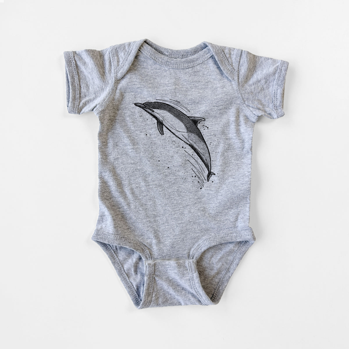 Grey baby bodysuit laid flat, printed with a black ink illustration of a common dolphin leaping, with ink splatters.