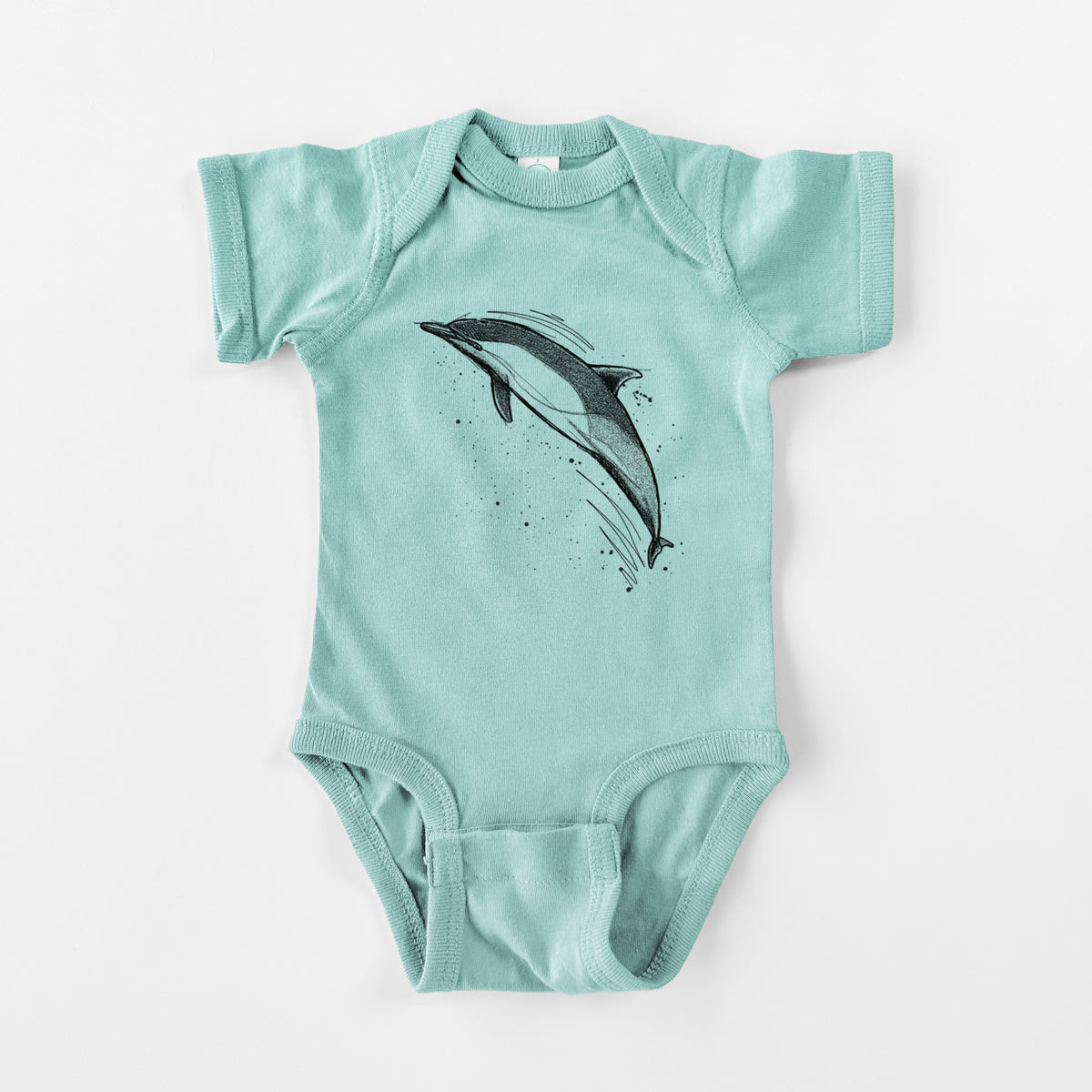 Saltwater baby bodysuit laid flat, printed with a black ink illustration of a common dolphin leaping, with ink splatters.