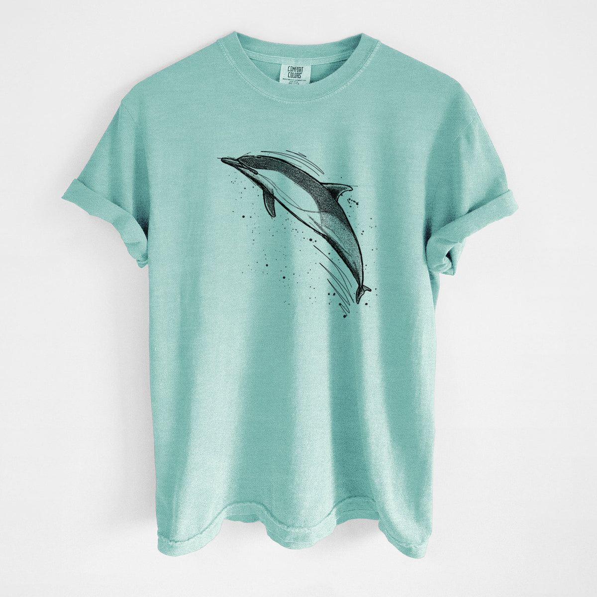 Chalky mint Comfort Colors t-shirt laid flat, printed with a black ink illustration of a common dolphin leaping, with ink splatters.