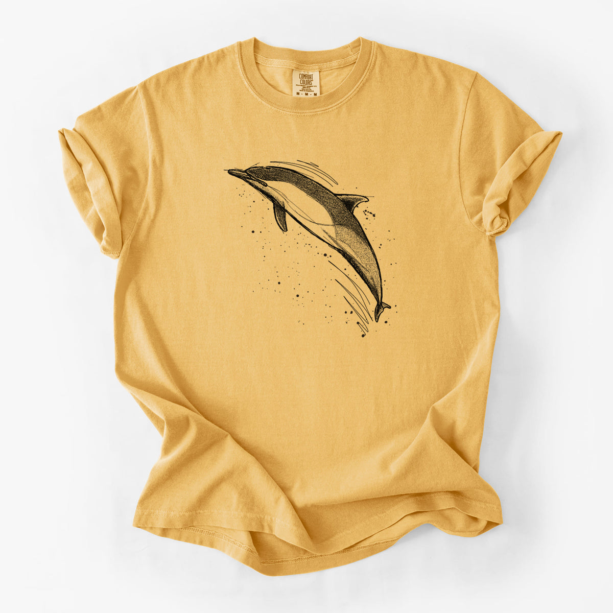 Golden wheat yellow Comfort Colors t-shirt laid flat, printed with a black ink illustration of a common dolphin leaping, with ink splatters.