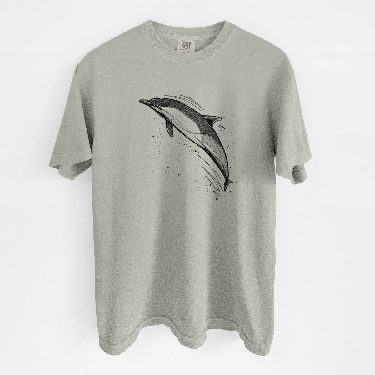 Sandstone beige Comfort Colors t-shirt laid flat, printed with a black ink illustration of a common dolphin leaping, with ink splatters.