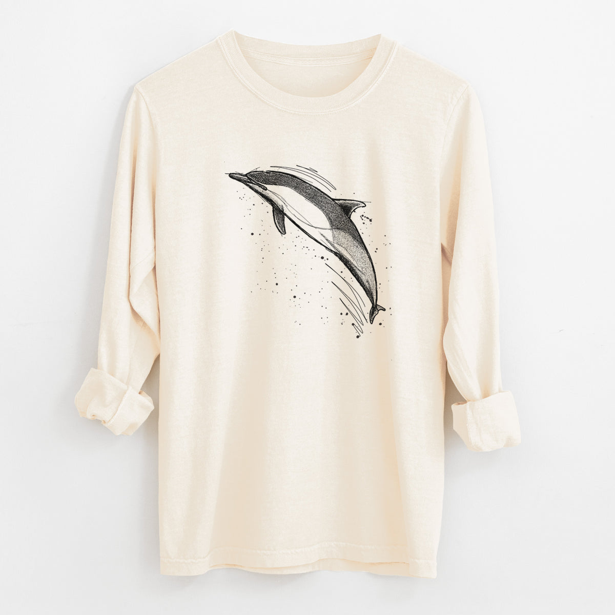 Ivory Comfort Colors long sleeve shirt laid flat with the cuffs rolled, printed with a black ink illustration of a common dolphin leaping, with ink splatters.