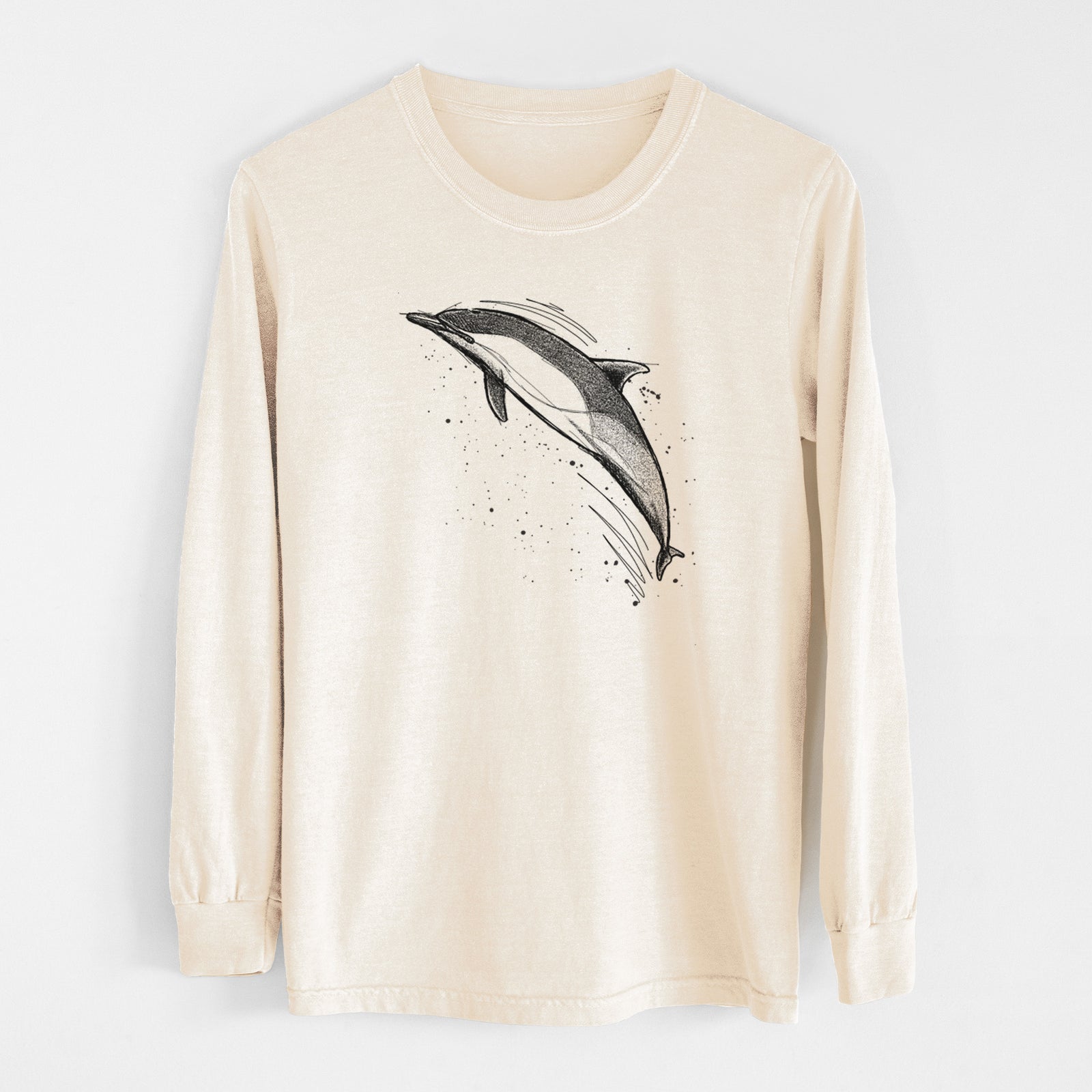 Ivory Comfort Colors long sleeve shirt laid flat, printed with a black ink illustration of a common dolphin leaping, with ink splatters.