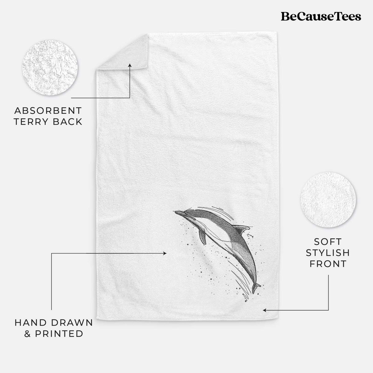 White hand towel printed with a black ink illustration of a common dolphin leaping, with ink splatters.