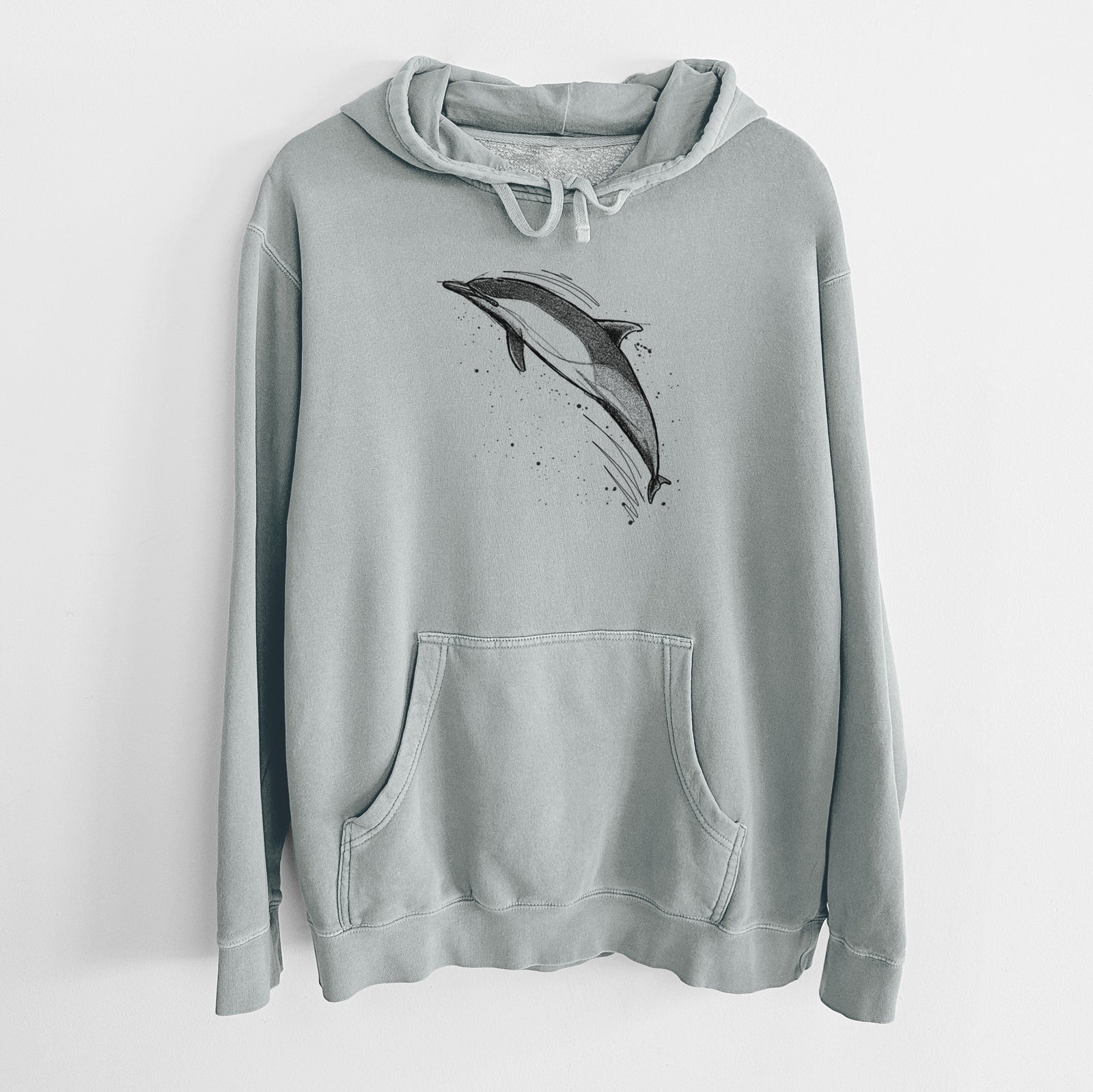 Sage green pigment dyed hoodie laid flat, printed with a black ink illustration of a common dolphin leaping, with ink splatters.