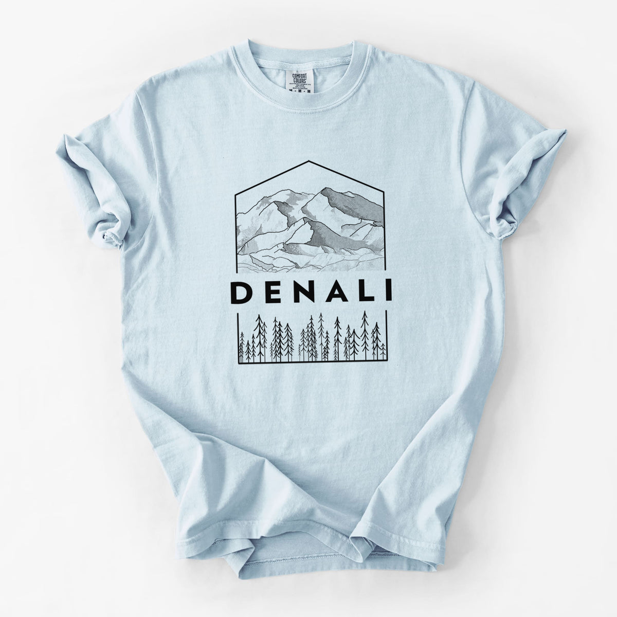 Chambray blue Comfort Colors t-shirt laid flat, printed with a black line art badge of the Denali mountain range above pine trees, with the word Denali.