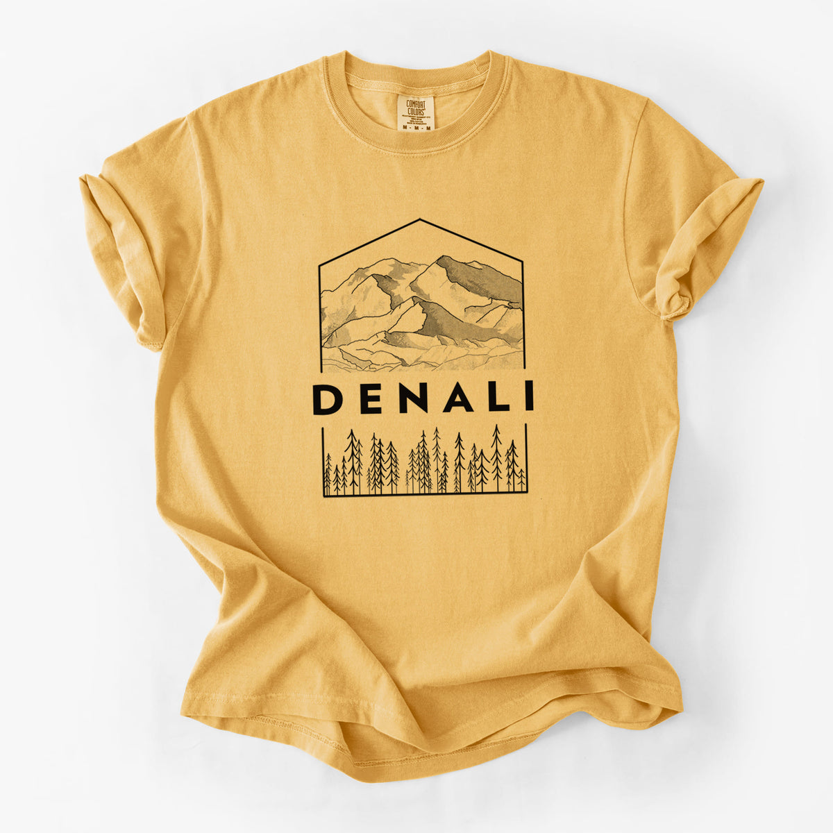 Golden wheat yellow Comfort Colors t-shirt laid flat, printed with a black line art badge of the Denali mountain range above pine trees, with the word Denali.