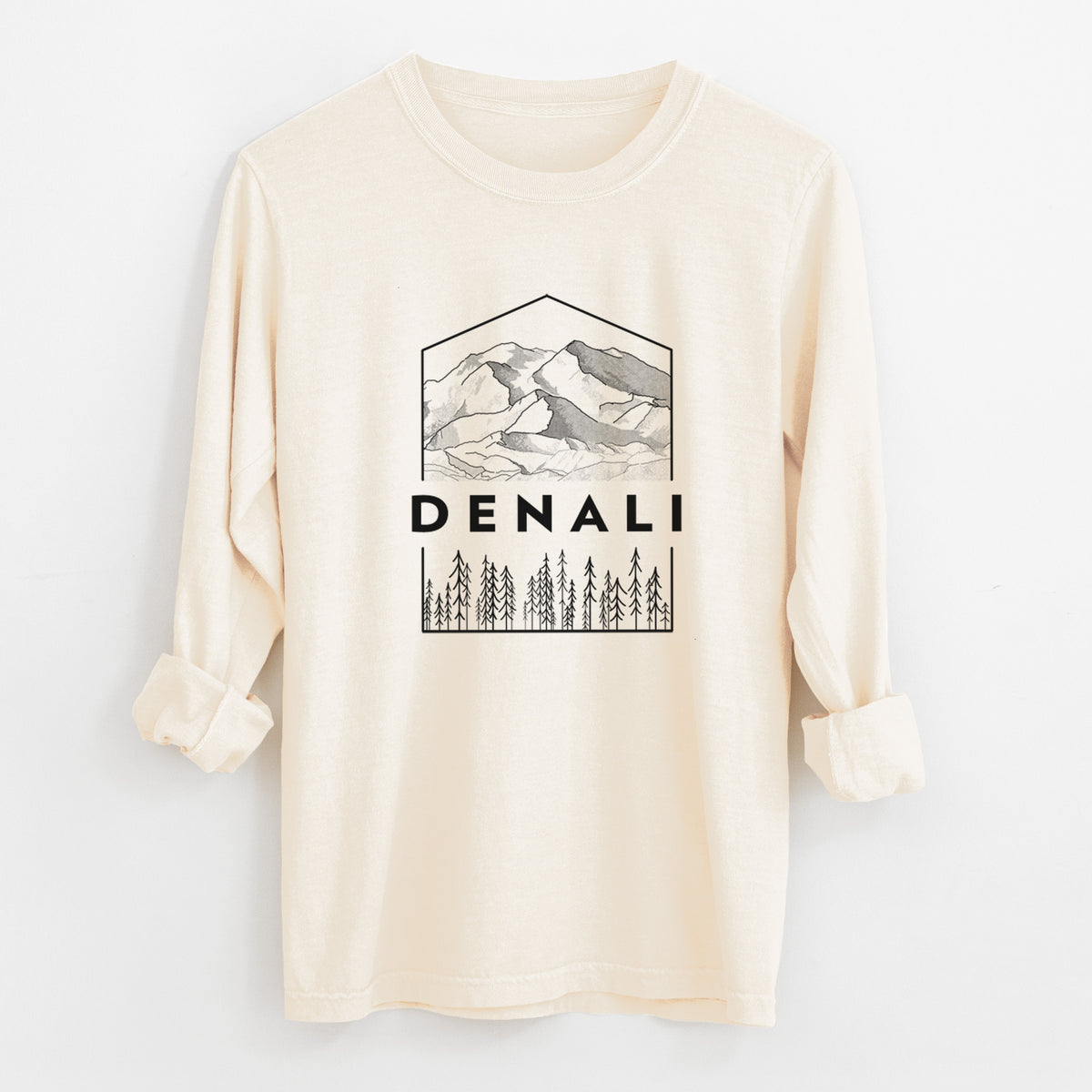 Ivory Comfort Colors long sleeve shirt laid flat with the cuffs rolled, printed with a black line art badge of the Denali mountain range above pine trees, with the word Denali.