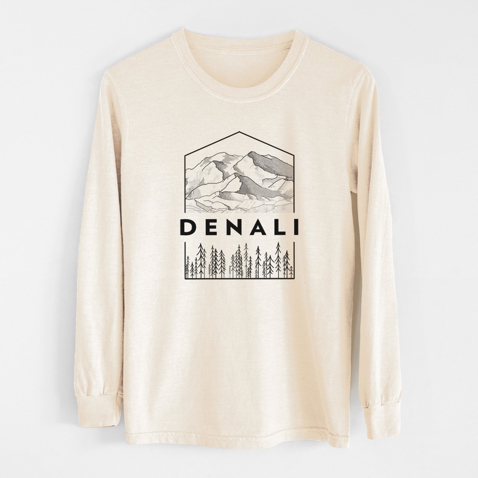 Ivory Comfort Colors long sleeve shirt laid flat, printed with a black line art badge of the Denali mountain range above pine trees, with the word Denali.