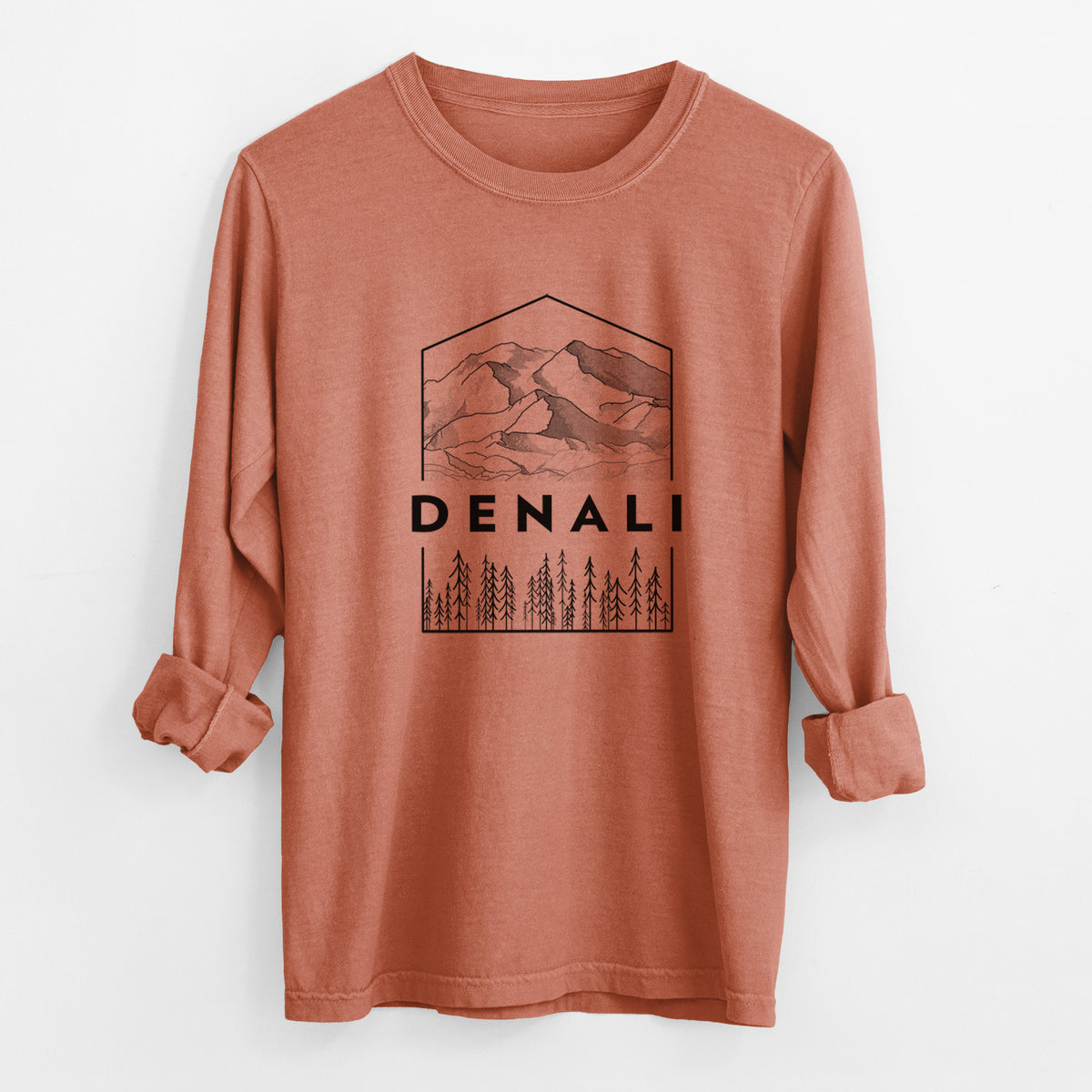 Yam burnt orange Comfort Colors long sleeve shirt laid flat with the cuffs rolled, printed with a black line art badge of the Denali mountain range above pine trees, with the word Denali.