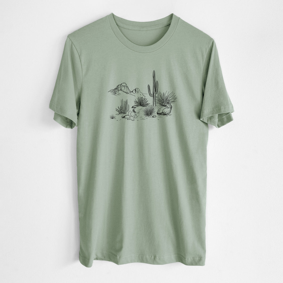 Sage green lightweight cotton t-shirt laid flat, printed with a black ink desert scene with a saguaro cactus, agave, rocks and distant mountains.