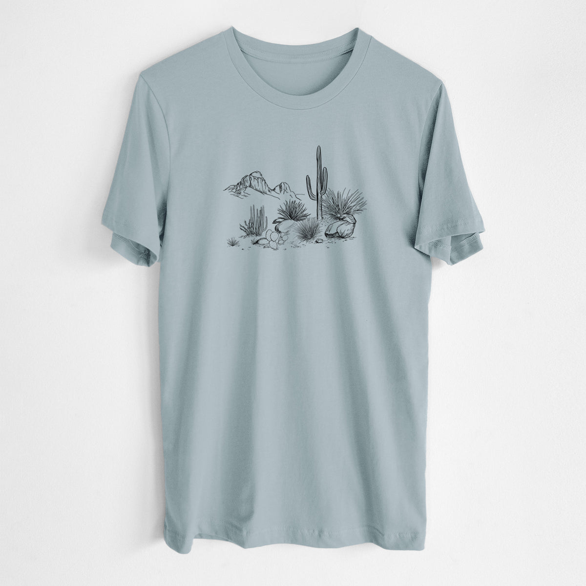 Vintage denim lightweight cotton t-shirt laid flat, printed with a black ink desert scene with a saguaro cactus, agave, rocks and distant mountains.