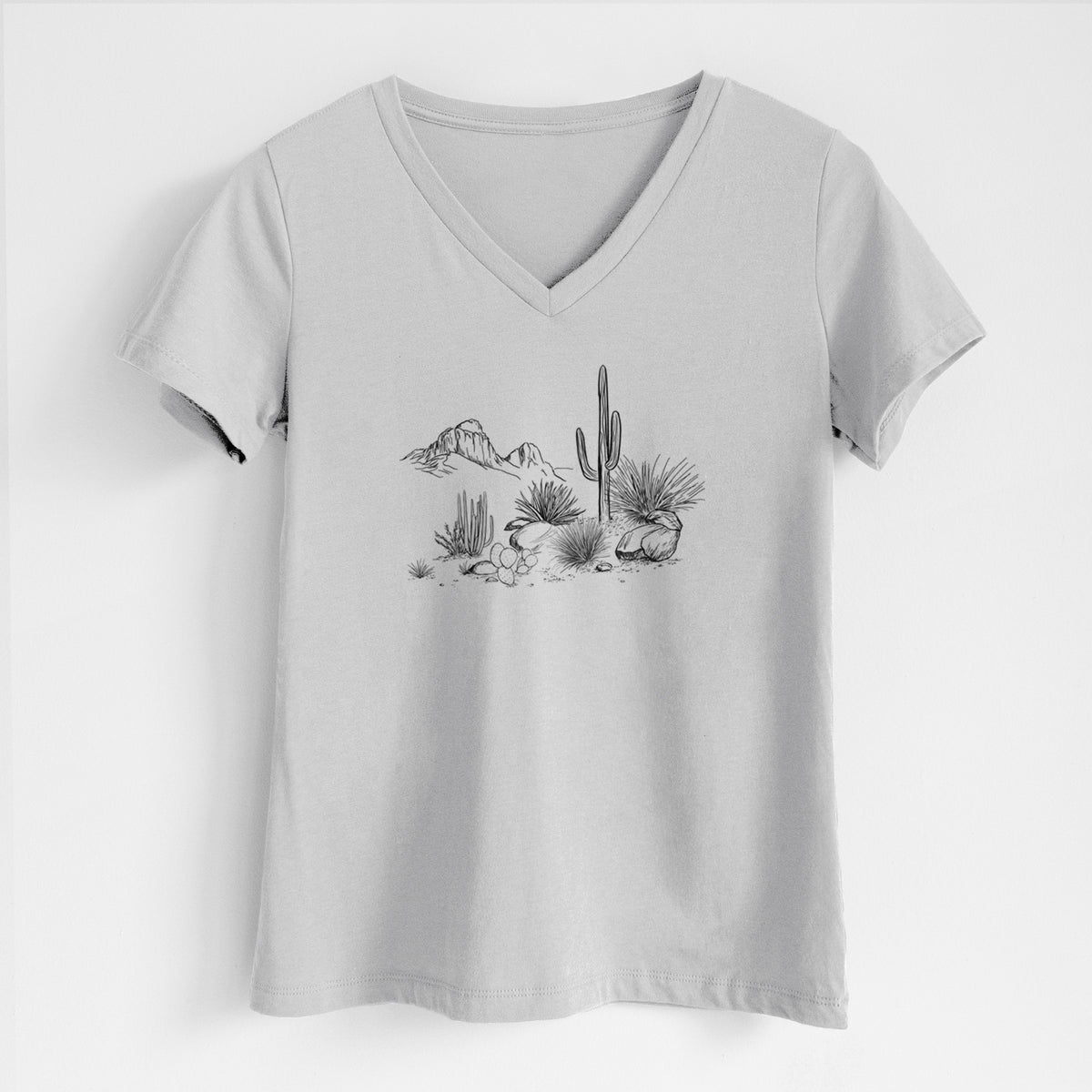 Lunar grey women's relaxed fit cotton V-neck t-shirt laid flat, printed with a black ink desert scene with a saguaro cactus, agave, rocks and distant mountains.