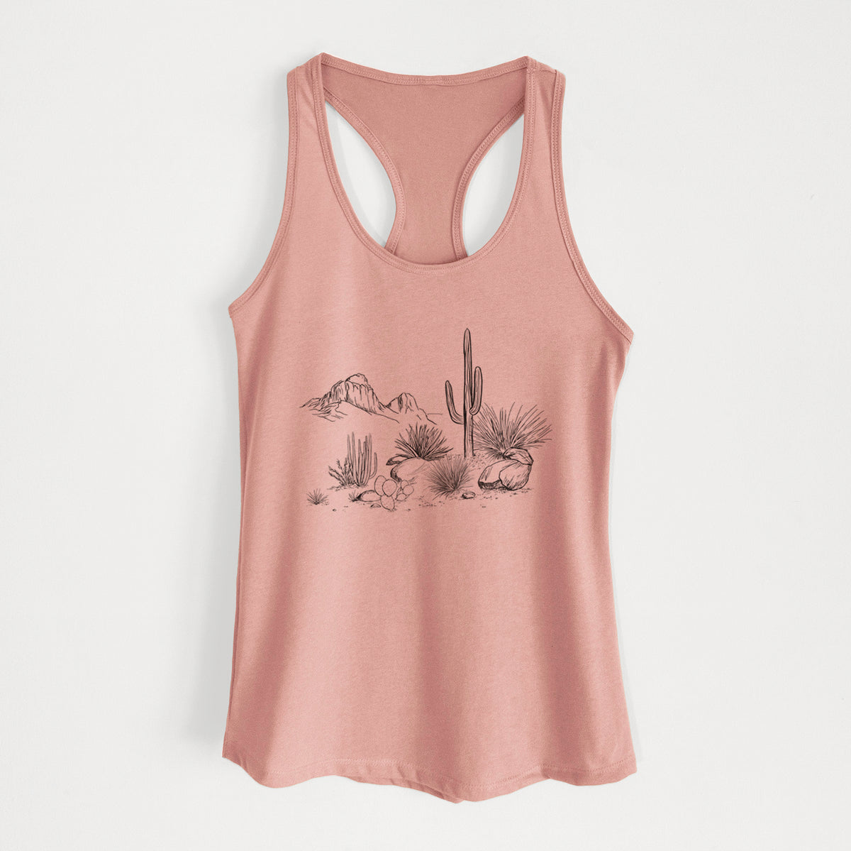 Desert pink women's racerback tank top laid flat, printed with a black ink desert scene with a saguaro cactus, agave, rocks and distant mountains.