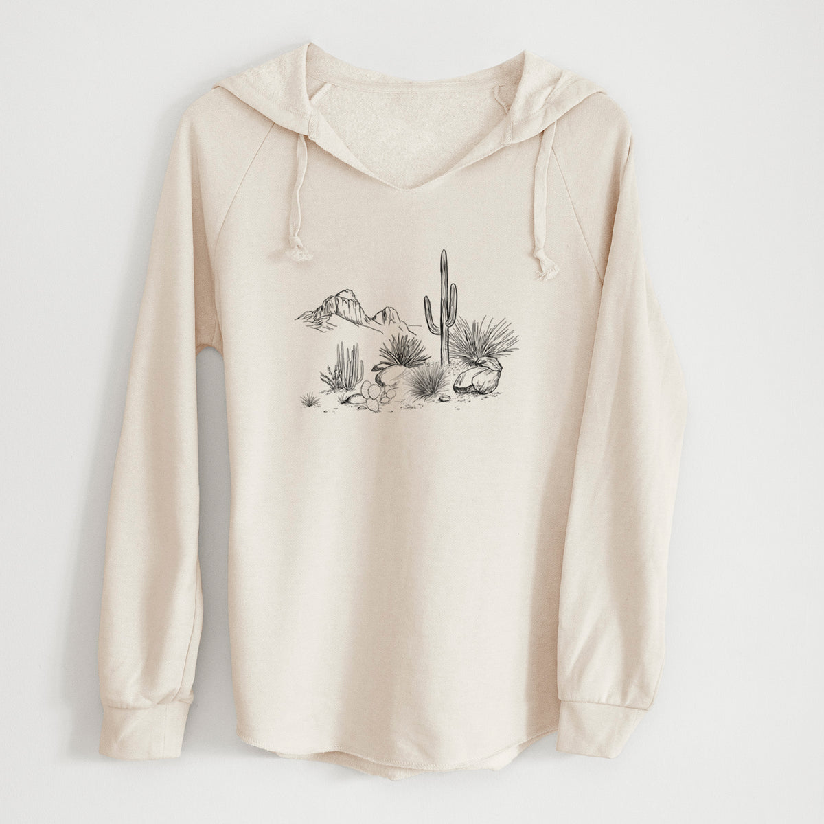 Bone cream women's Cali Wave hooded sweatshirt laid flat, printed with a black ink desert scene with a saguaro cactus, agave, rocks and distant mountains.