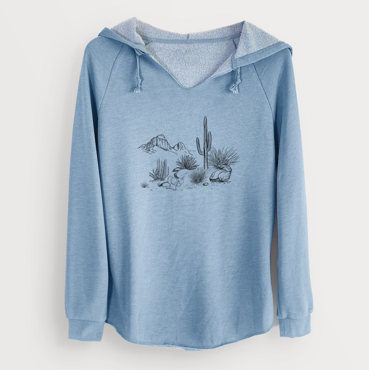 Misty blue women's Cali Wave hooded sweatshirt laid flat, printed with a black ink desert scene with a saguaro cactus, agave, rocks and distant mountains.