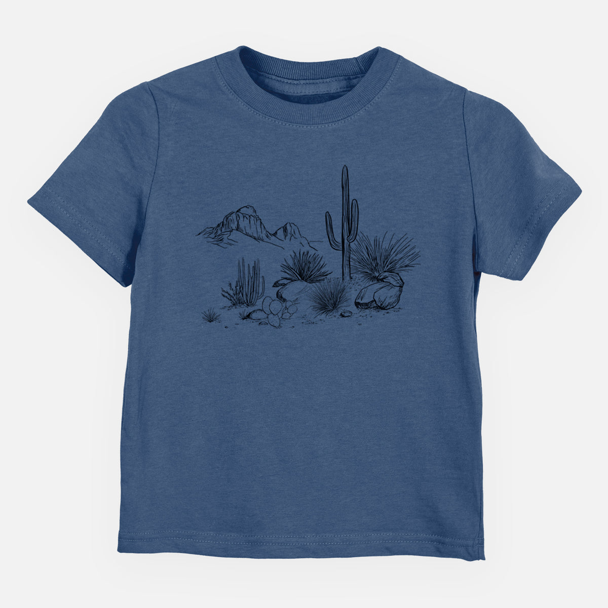Indigo blue toddler t-shirt laid flat, printed with a black ink desert scene with a saguaro cactus, agave, rocks and distant mountains.
