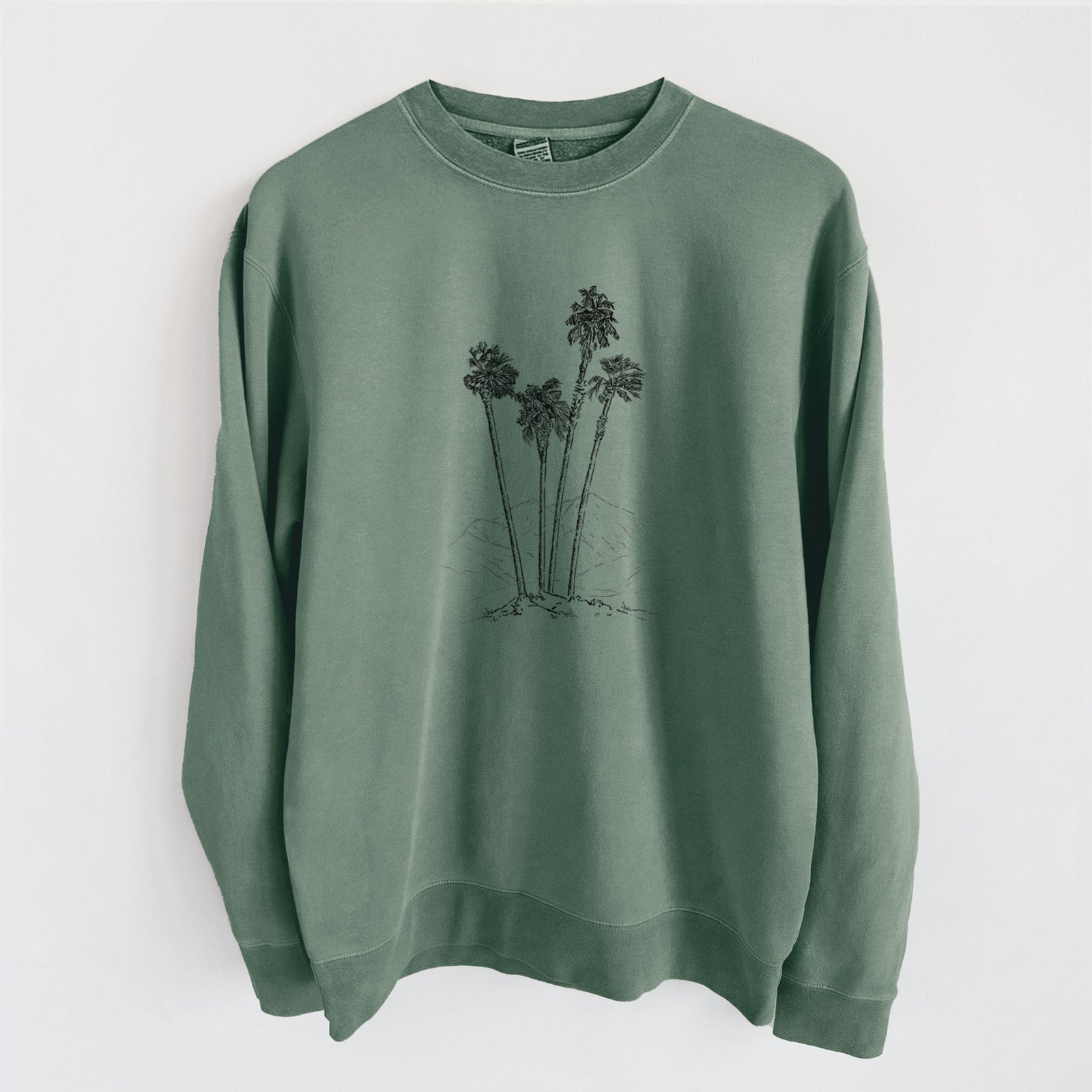 Alpine green pigment dyed crewneck sweatshirt laid flat, printed with a black ink illustration of a cluster of tall desert palm trees.